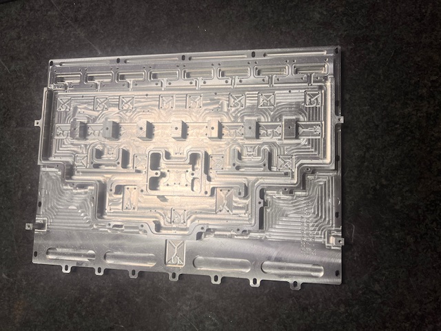 Finished machined aluminum component placed on a dark inspection surface