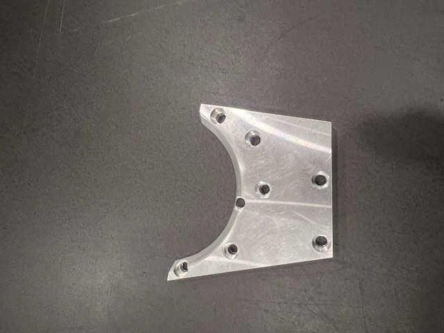 Finished machined aluminum part displayed on a dark work surface
